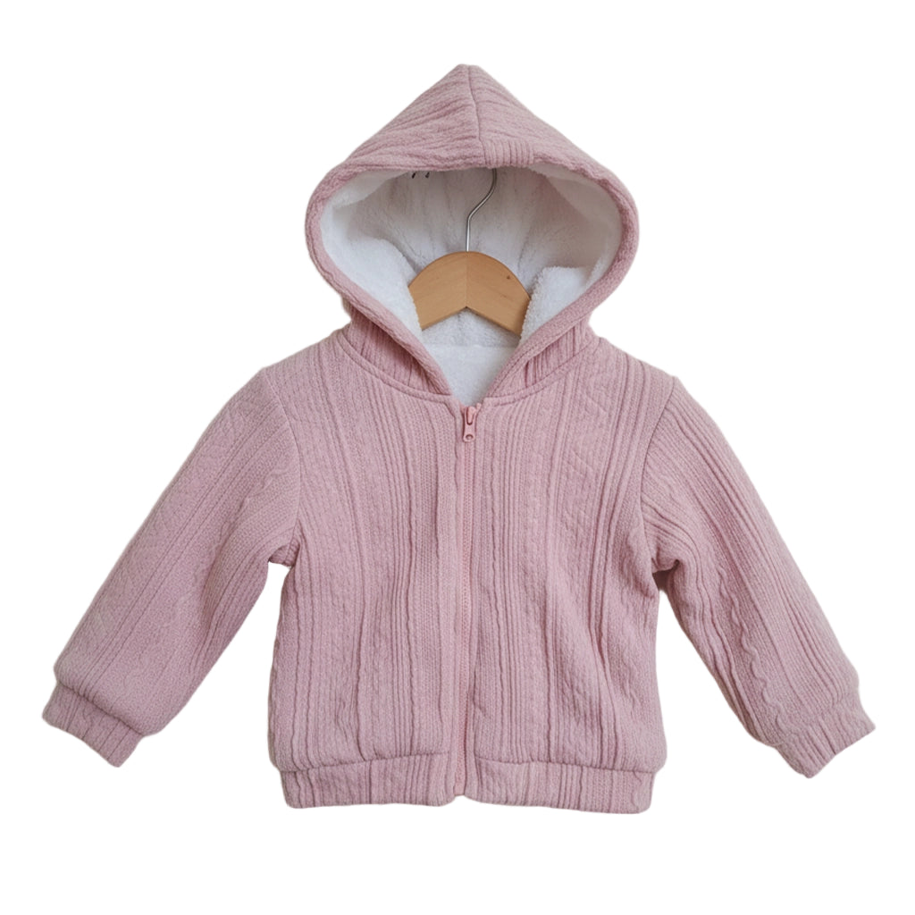 Pink children's hoodie on a wooden hanger against a light background