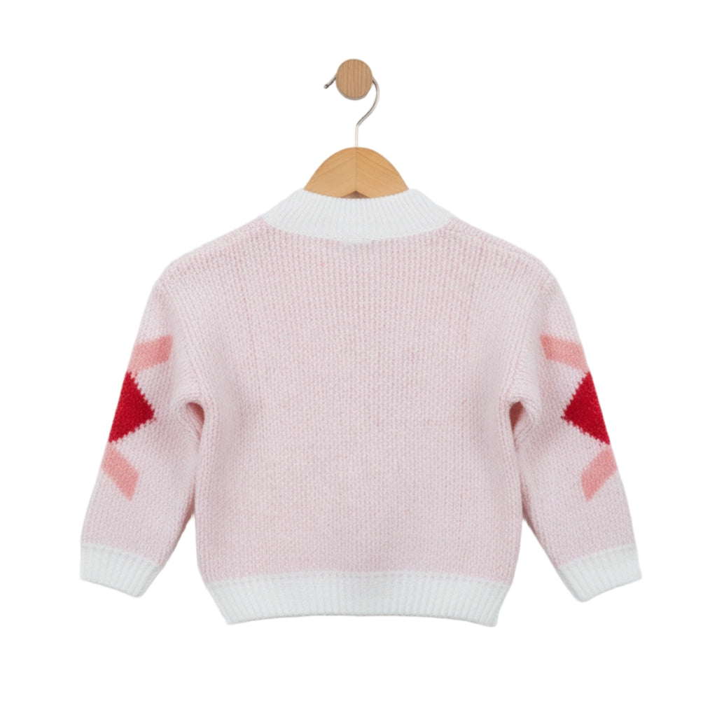 Pink sweater with red and white pattern on sleeves, hanging on a wooden hook against a white background.