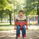 Child on a swing in a park with trees and playground equipment in the background