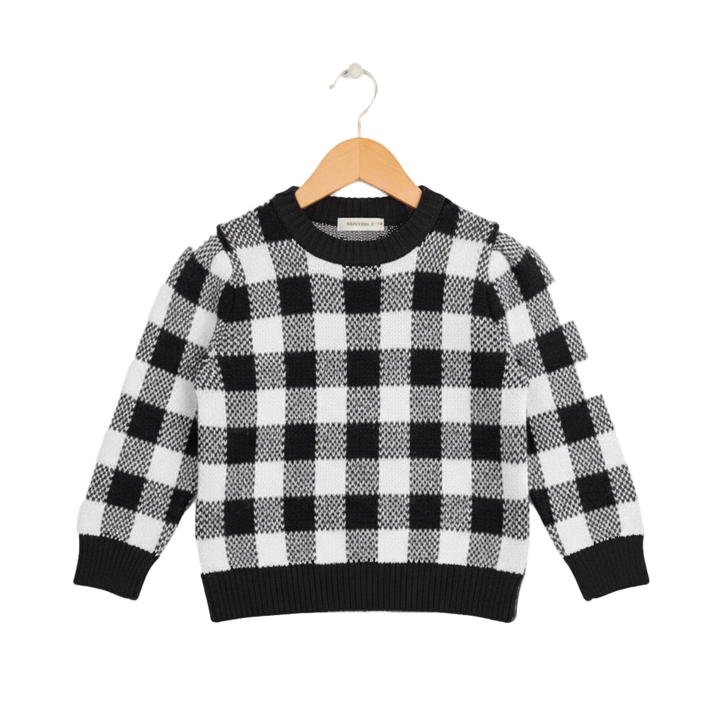 Black and white checkered sweater on a wooden hanger against a white background