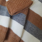 Close-up of a knitted fabric with brown, gray, and white stripes.