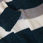 Close-up of a knitted fabric with blue, white, and gray stripes.