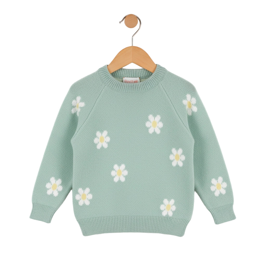 Green sweater with white daisy patterns on a wooden hanger against a white background