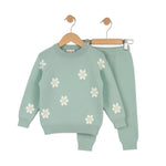 Green children's sweater with white daisy patterns on a white background