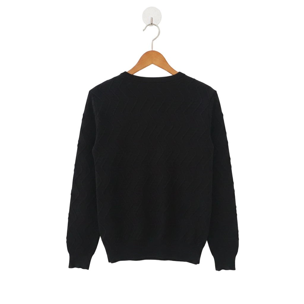 Black sweater on a wooden hanger against a white background