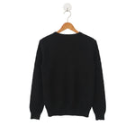 Black sweater on a wooden hanger against a white background