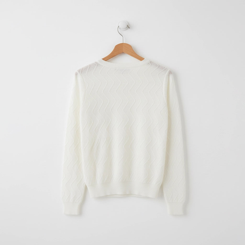 White sweater on a wooden hanger against a white background