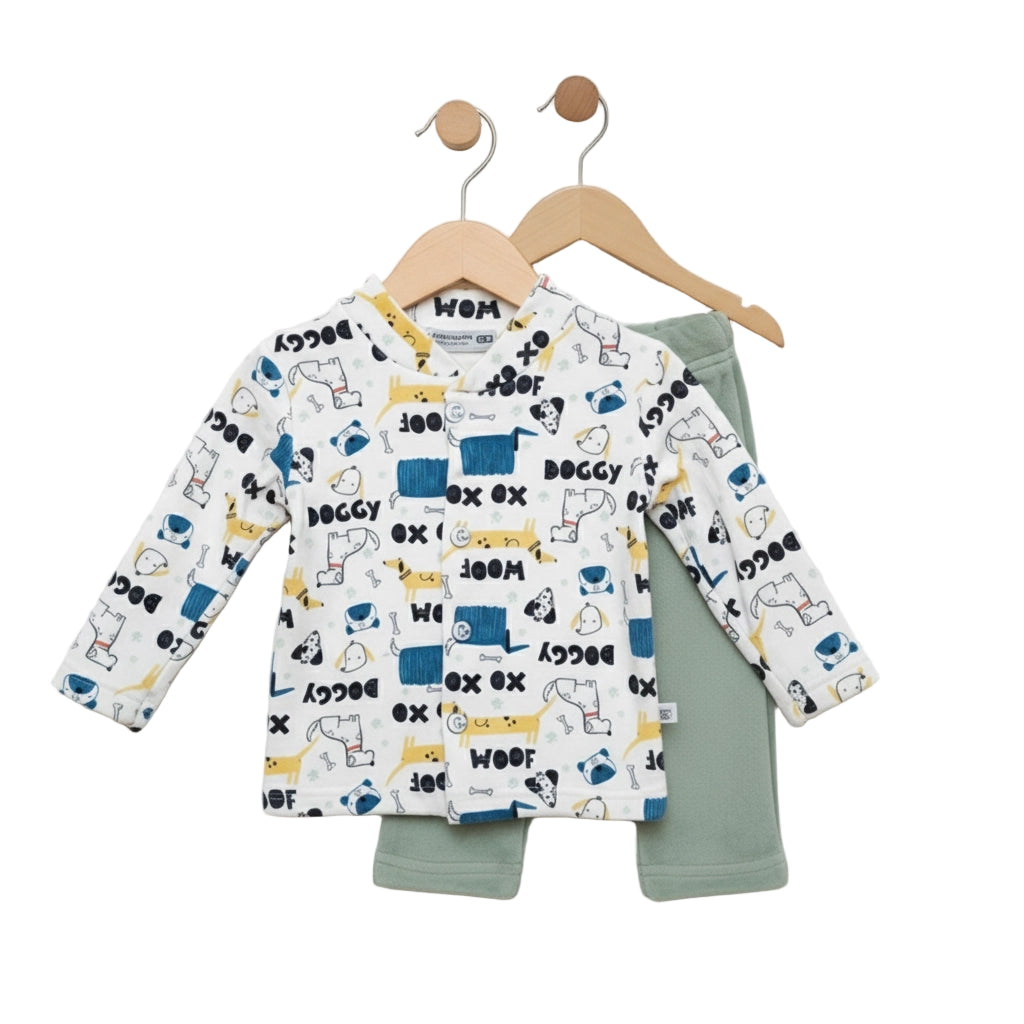 Children's outfit with patterned long-sleeve shirt and green pants on hangers against a white background
