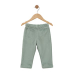 Green baby pants on a wooden hanger against a white background