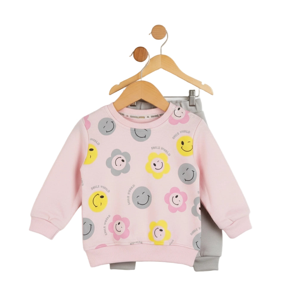 Pink children's sweatshirt with smiley face patterns on a hanger against a white background