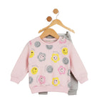 Pink children's sweatshirt with smiley face patterns on a hanger against a white background
