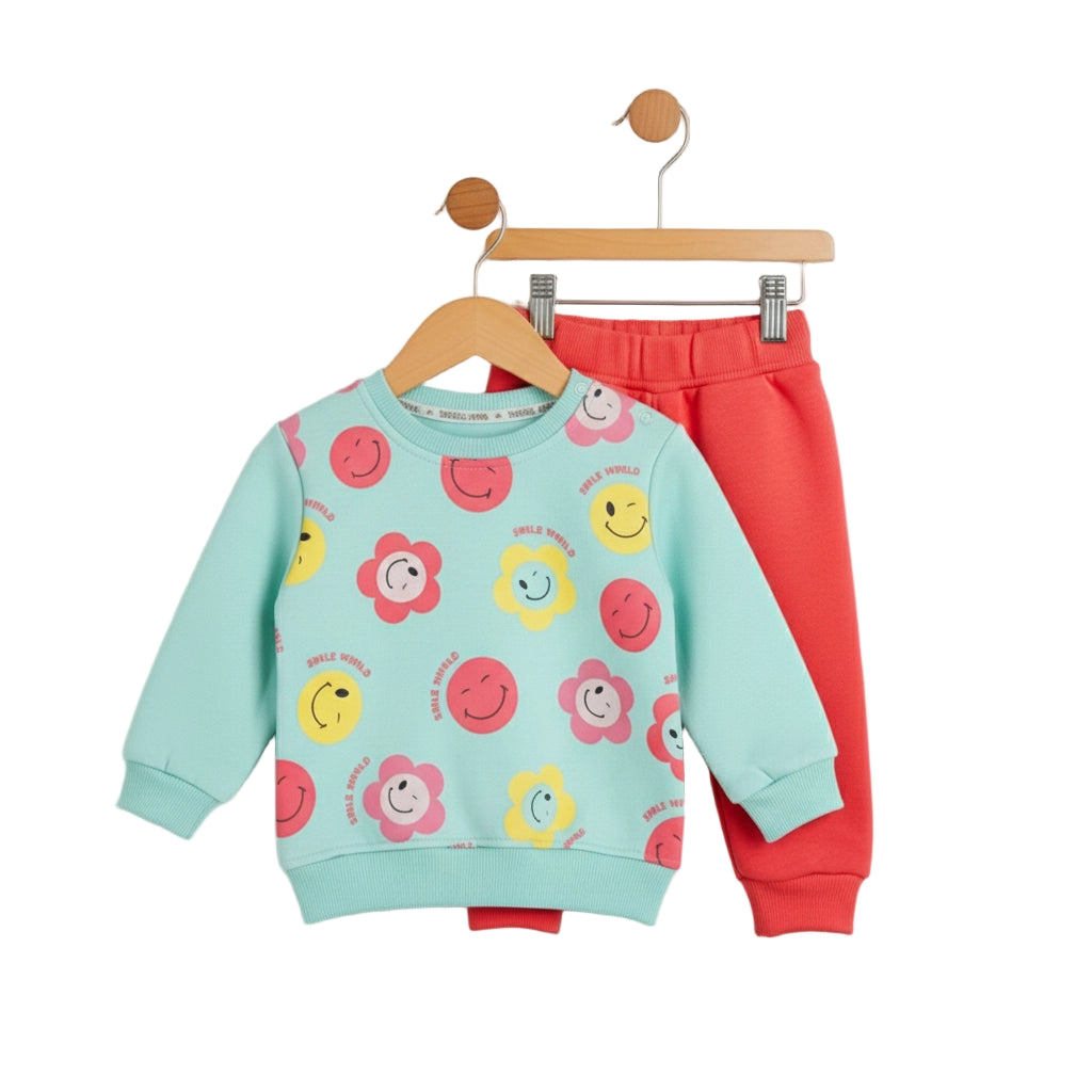Children's outfit with a colorful top and red pants on a hanger against a white background
