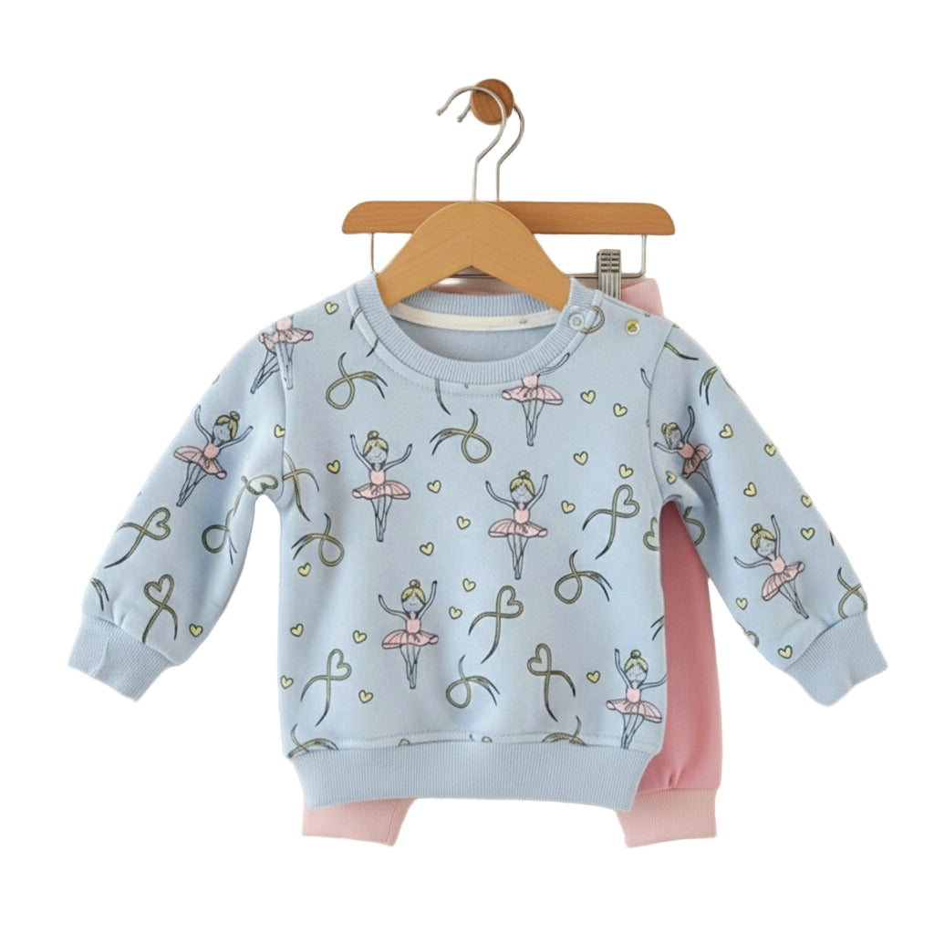Children's outfit with a light blue long-sleeve top and pink pants on a wooden hanger against a white background.