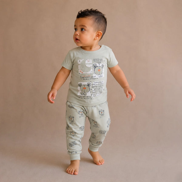 Child wearing a light green pajama set with animal prints on a beige background