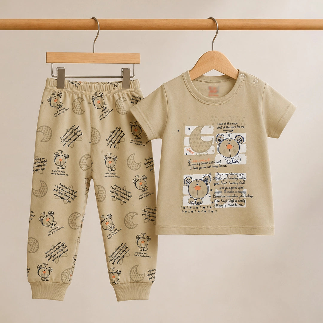 Children's beige outfit with printed shirt and pants on hangers against a beige background