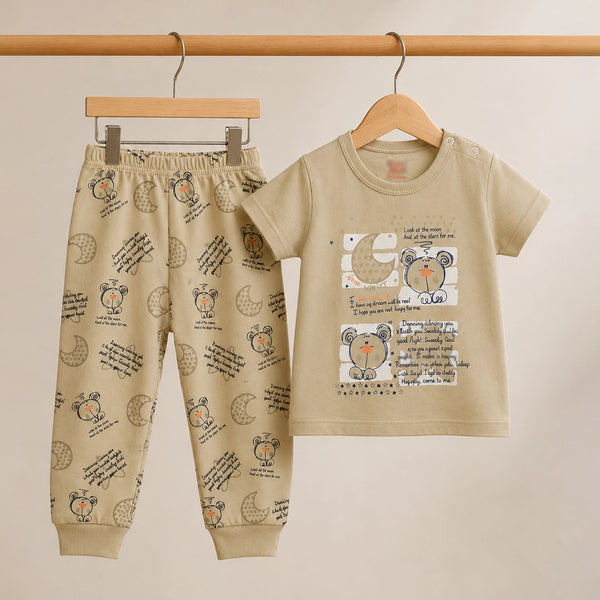 Children's beige outfit with printed shirt and pants on hangers against a beige background