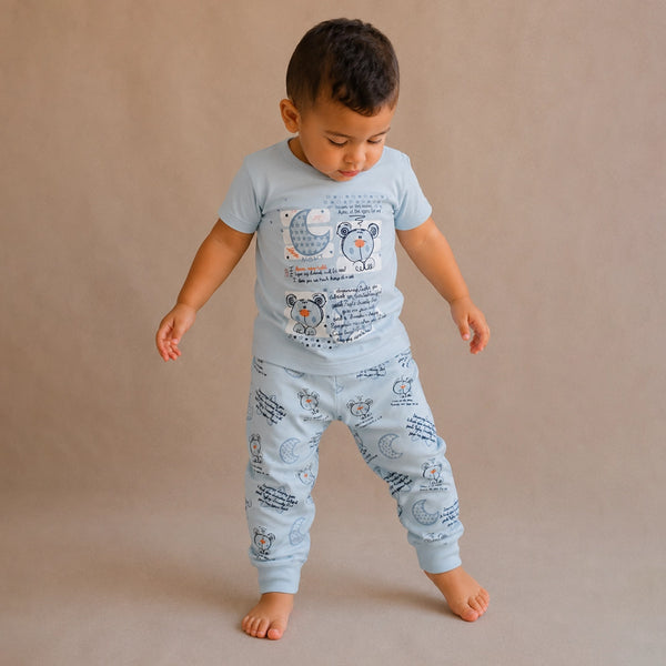 Child wearing a light blue pajama set with teddy bear designs on a beige background