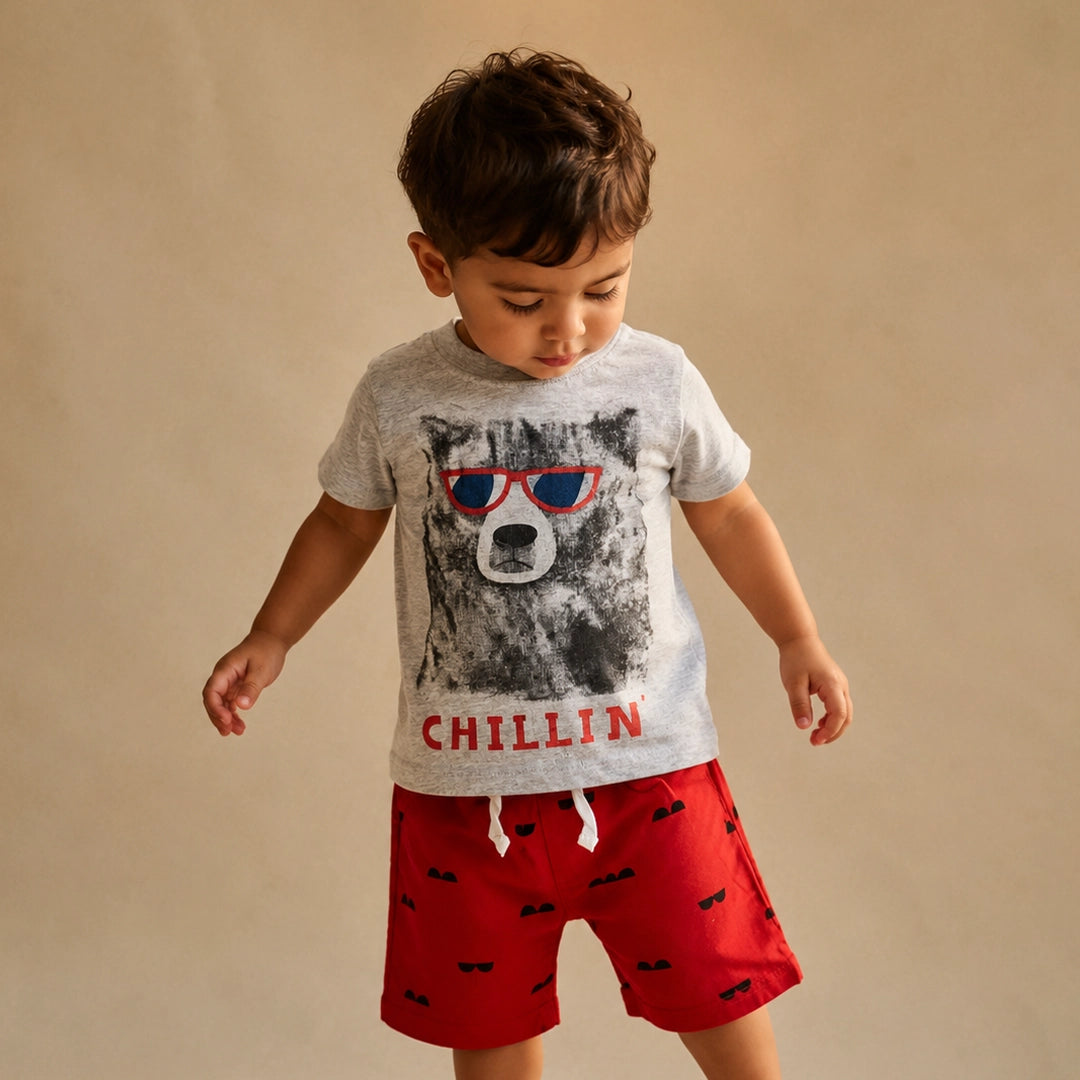 Child wearing a gray t-shirt with a bear graphic and red shorts on a beige background