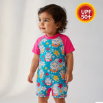 Child wearing a colorful swimsuit with cartoon characters on a light gray background, featuring a UPF 50+ label.