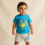 Child wearing a blue t-shirt with a dinosaur and rubber duck graphic, and gray shorts with 'Hello Summer' text.