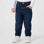 Toddler wearing blue jeans and white sneakers on a plain background