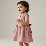 Child wearing a pink floral dress on a plain background