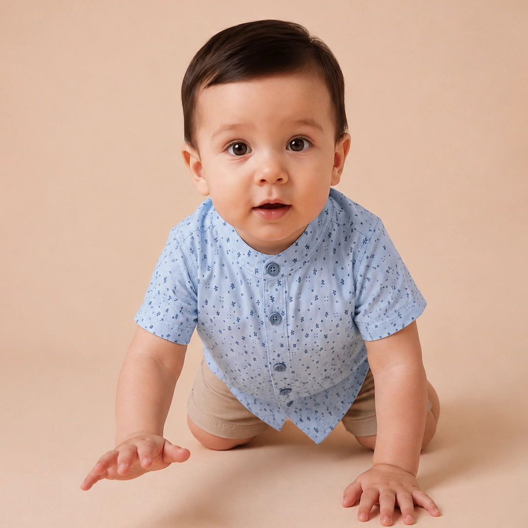 Child wearing a light blue shirt with small patterns and dark jeans on a plain background