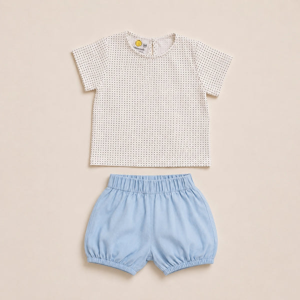 Children's outfit with blue shorts and patterned shirt on hangers against a beige background