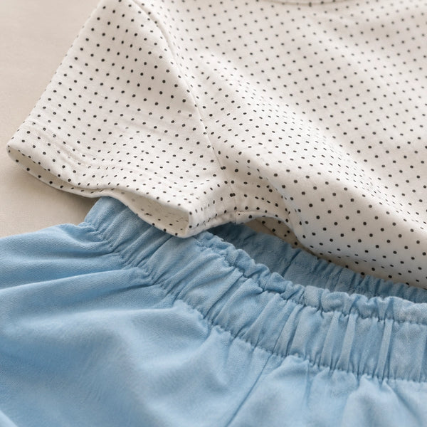 Close-up of a polka dot top and light blue pants on a neutral background