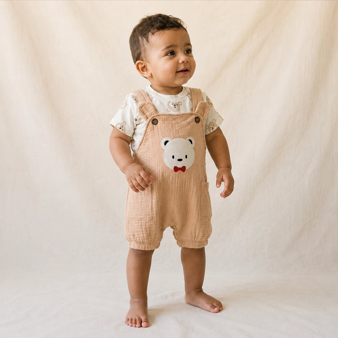 Baby wearing a beige romper with a bear face design on a plain background