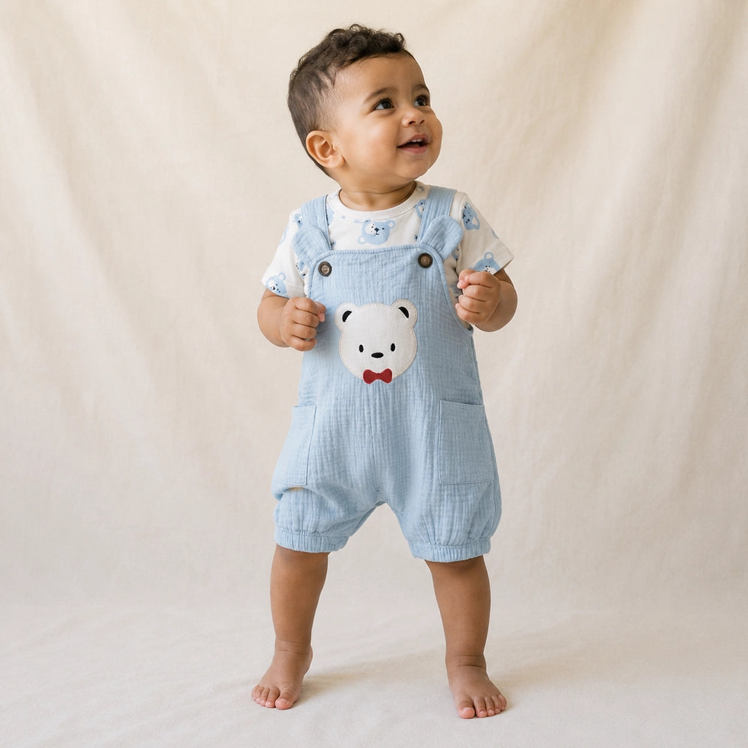 Baby wearing a light blue romper with a bear design on a neutral background