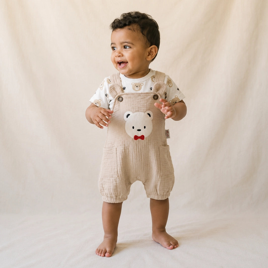 Baby wearing a beige romper with a bear design on a plain background