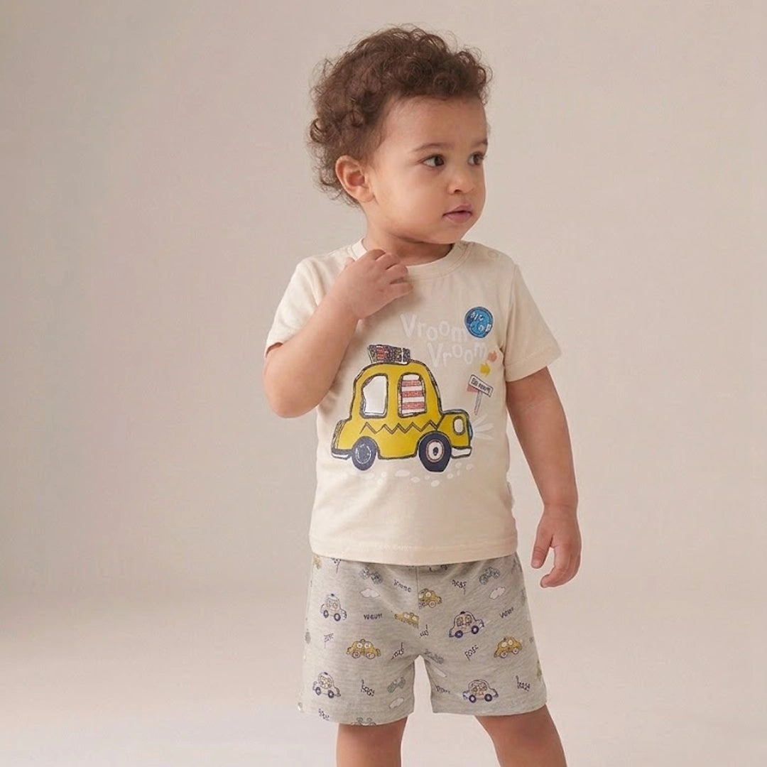 Child wearing a white t-shirt with a yellow taxi graphic and gray shorts with vehicle pattern on a plain background