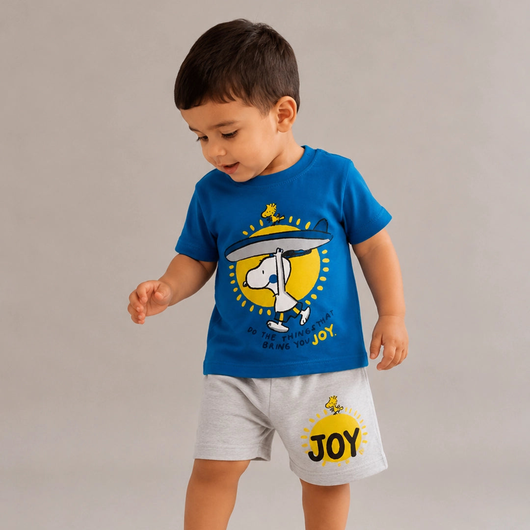 Child wearing a blue t-shirt and gray shorts with a 'JOY' design on a plain background