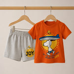 Orange t-shirt with cartoon character and gray shorts with 'JOY' print on hangers against a beige background
