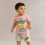Child wearing a pink t-shirt with a cartoon character and gray shorts on a beige background