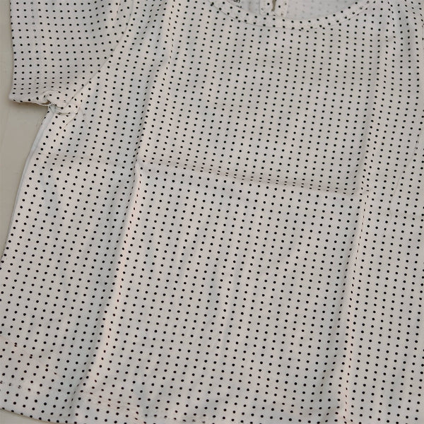 Close-up of a white shirt with black dot pattern on a light gray background