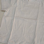 Close-up of a white shirt with black dot pattern on a light gray background