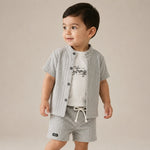 Child wearing a striped shirt and shorts set with a plain background