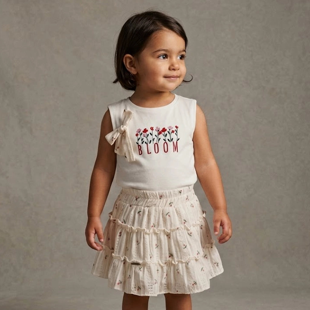 Girl wearing a skirt set with Bloom written on the top and a bow