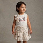 Girl wearing a skirt set with Bloom written on the top and a bow