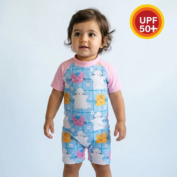 Child wearing a colorful swimsuit with cartoon designs on a light blue background, featuring a UPF 50+ label.
