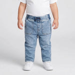 Child wearing light blue jeans and white shoes on a plain background
