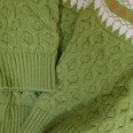Close-up of a green knitted sweater with cable pattern