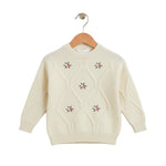 Cream-colored sweater with floral embroidery on a wooden hanger against a white background