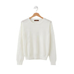 White sweater on a wooden hanger against a white background