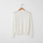 White sweater on a wooden hanger against a white background