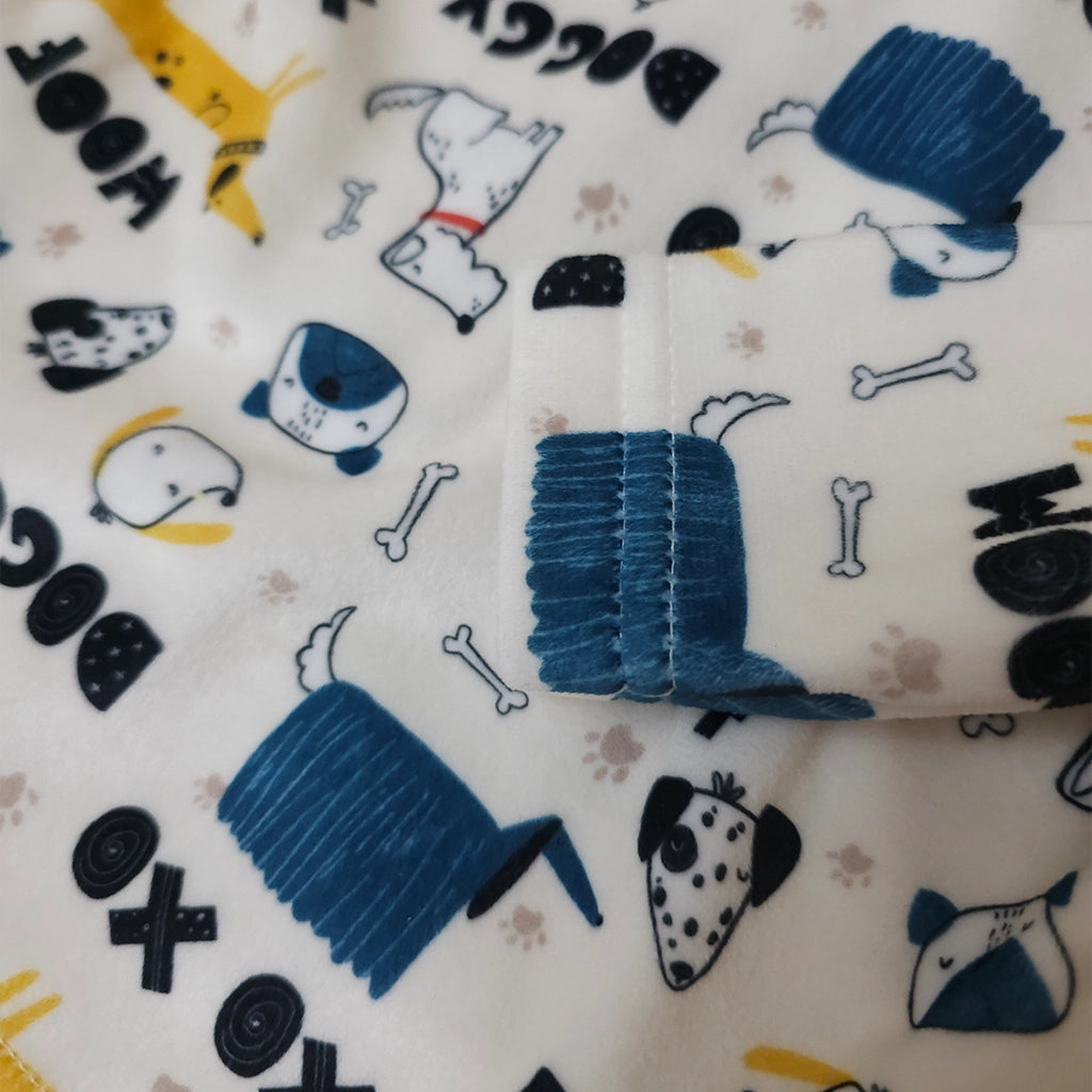 Close-up of a fabric with dog-themed patterns and a blue brush on a white background.