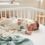 Baby sleeping in a crib with a soft blanket