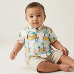 Child wearing a colorful shirt with beach-themed design on a gray background